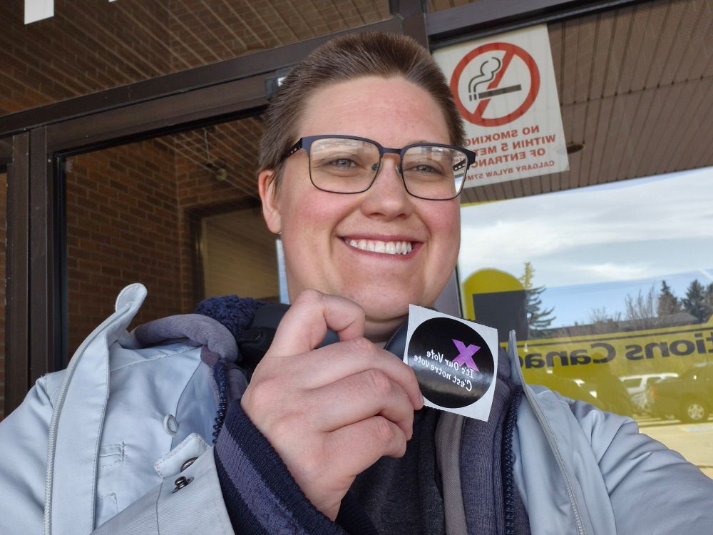 Photo of me in front of a polling station holding up a "It's Our Vote" sticker
