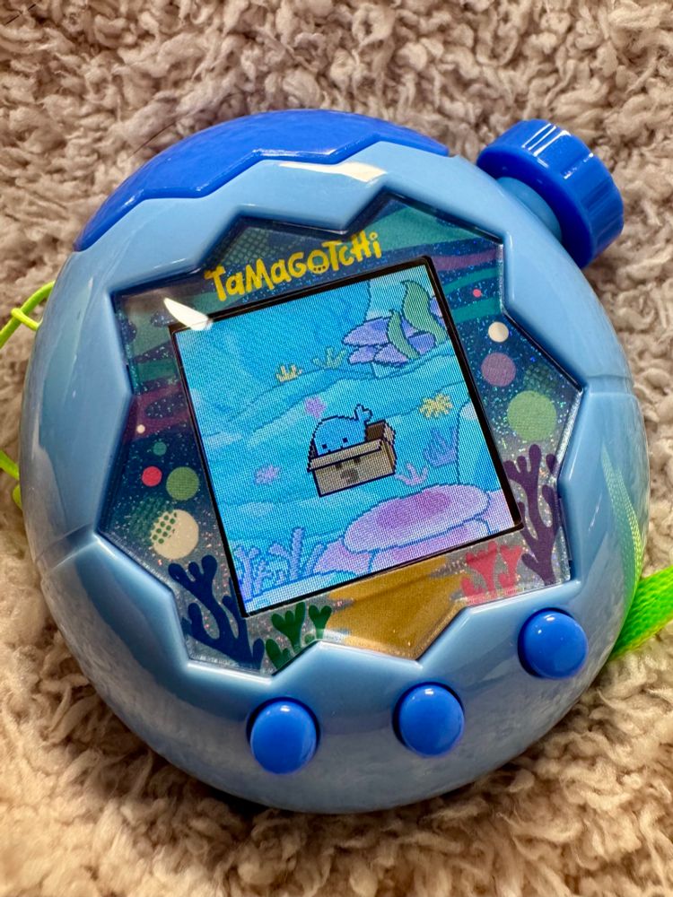 Once more a photo of the tamagotchi paradise, the tama has evolved again into a whale-like blob and is sitting in a box placed in its ocean environment