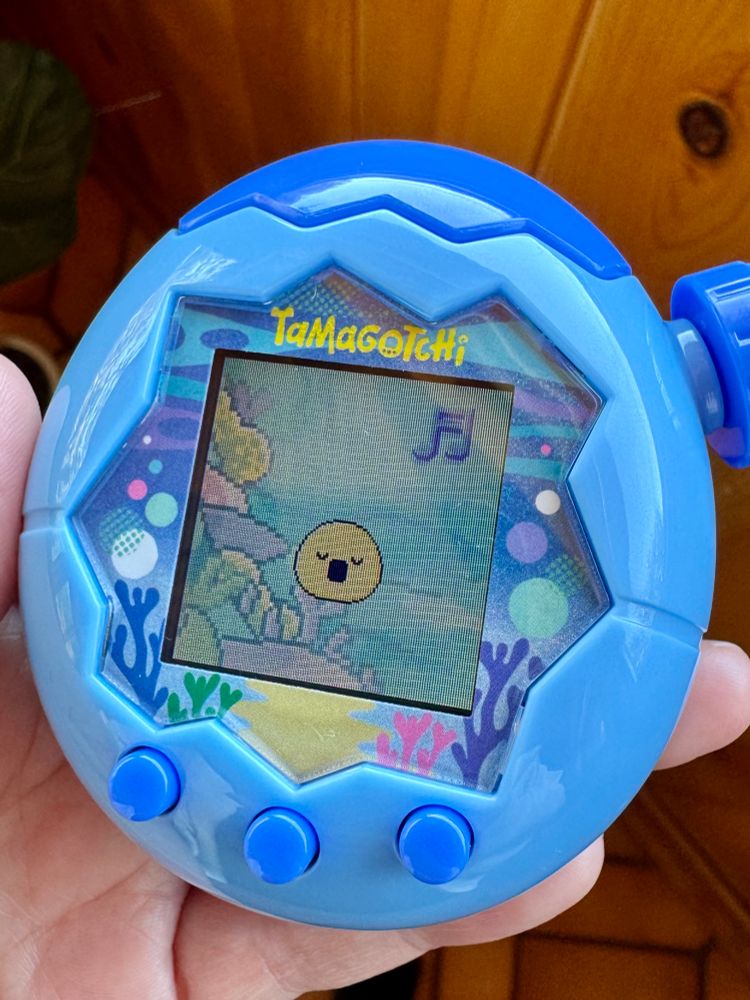 Photo of a Tamagotchi Paradise showing a baby form tama happy and singing in an ocean environment
