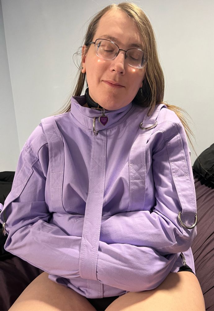 A brunette woman, sleepyhead, wearing a lavender straight jacket 