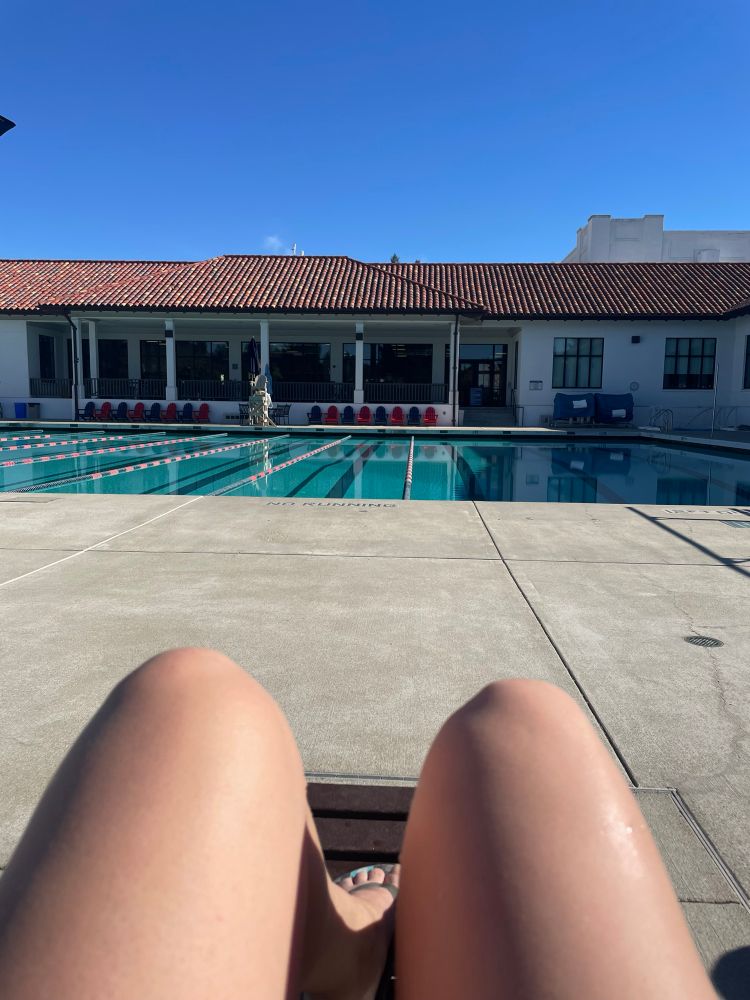 My legs in front of a pool. 