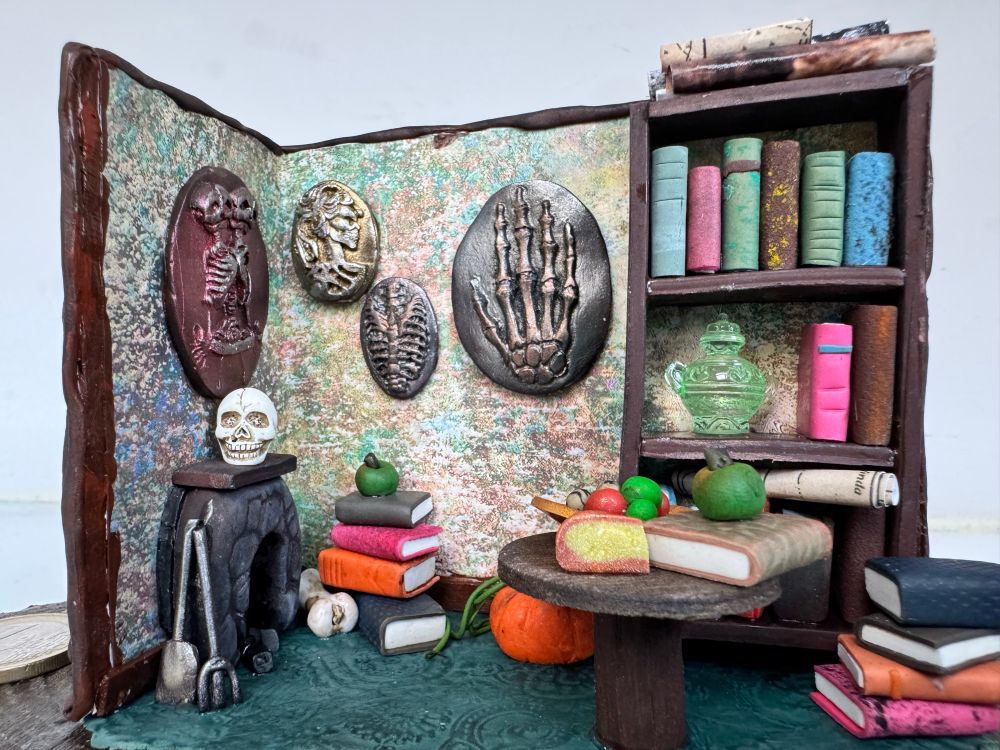 Maqueta de una habitación, se ven imágenes algo macabras en las paredes y muchos libros