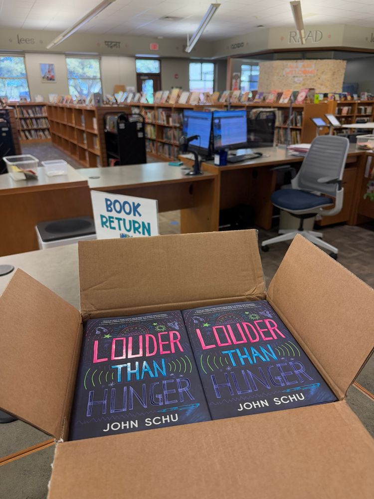 photo contains a box of books; Louder Than Hunger by John Schu