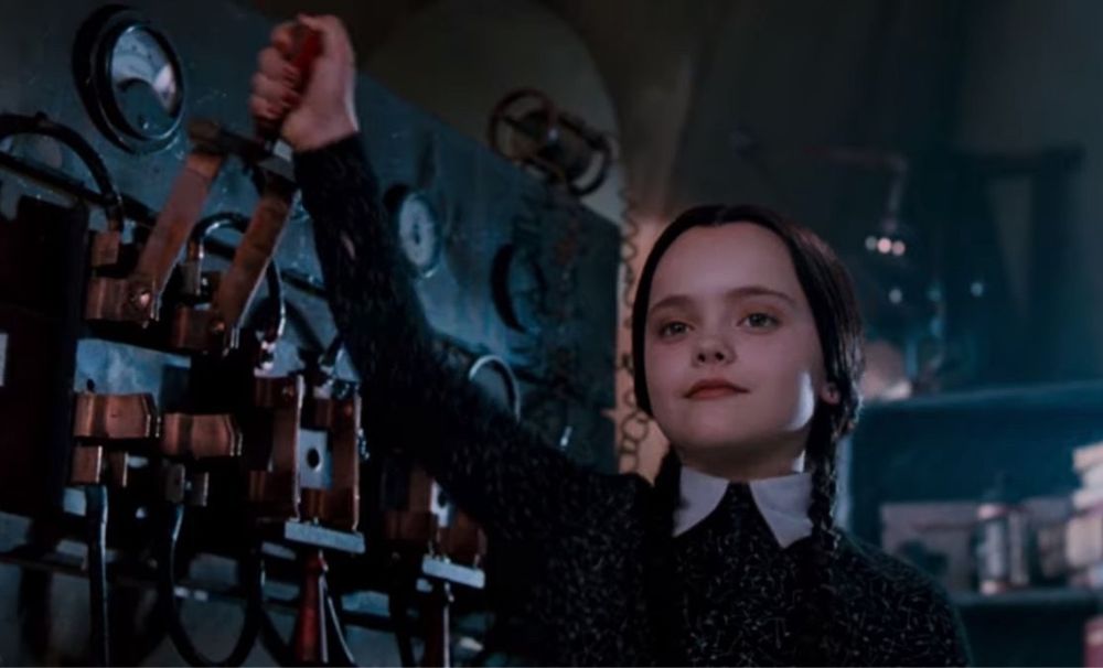Wednesday Addams about to pull the lever of the electric chair. She looks self satisfied.