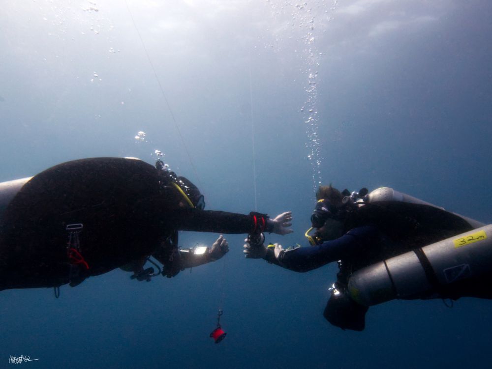 Two scuba divers performing drills with SMBs in the blue