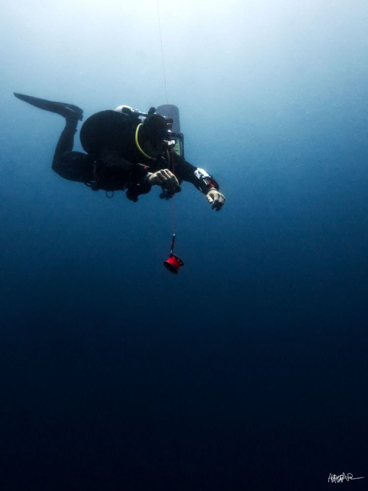 Single scuba diver holding an SMB reel in the blue
