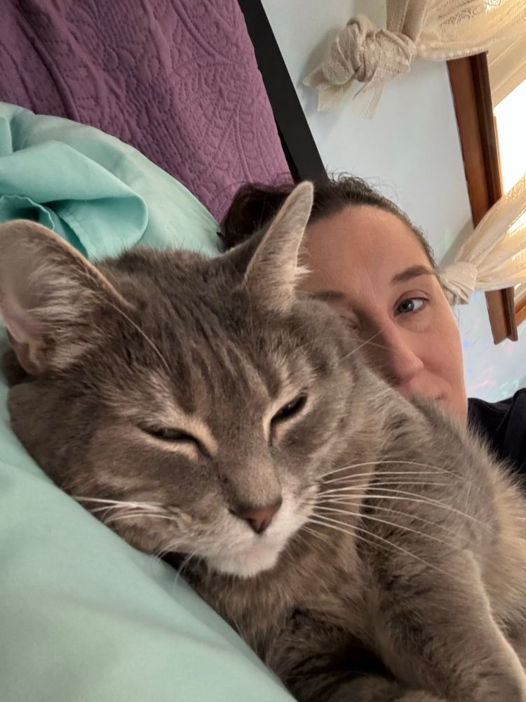Angela and her cat, Gracie, snuggling in bed. 