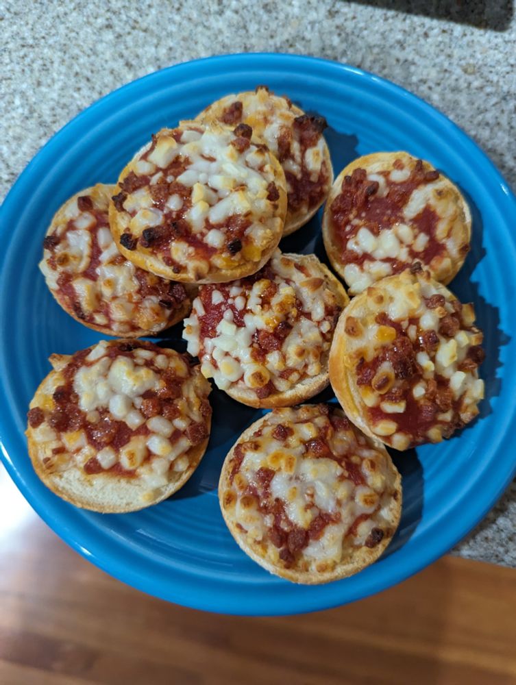 Eight pepperoni bagel bites on a small, blue plate