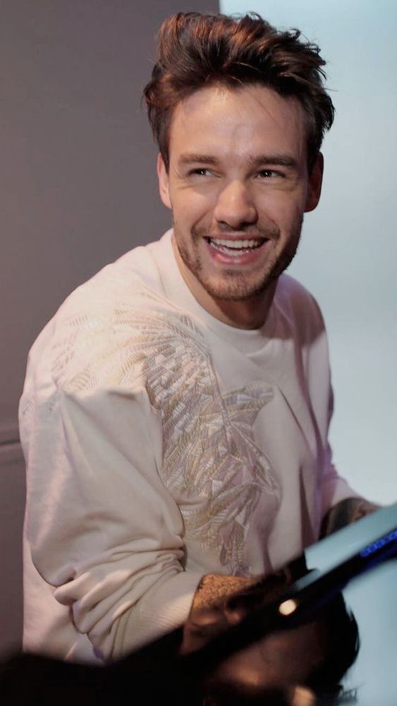Liam Payne smiling in a beautiful white shirt at a piano