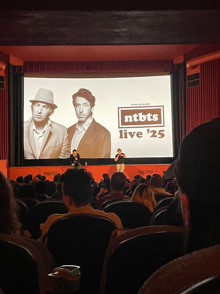 Blurry photo of Matt Johnson (no relation) and Jay McCarrol at the front of a theatre, doing a Q&A for Nirvanna The Band The Show The Movie The Tour