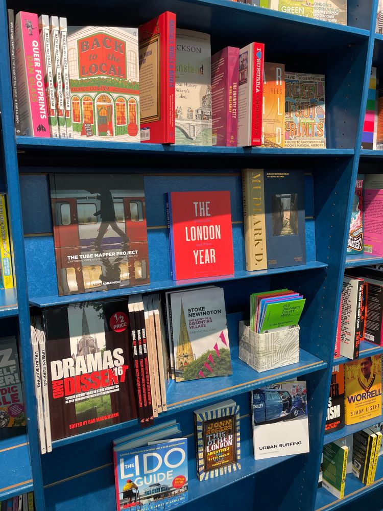 A blue bookshelf with various books about London, including “The Tube Mapper Project”. 