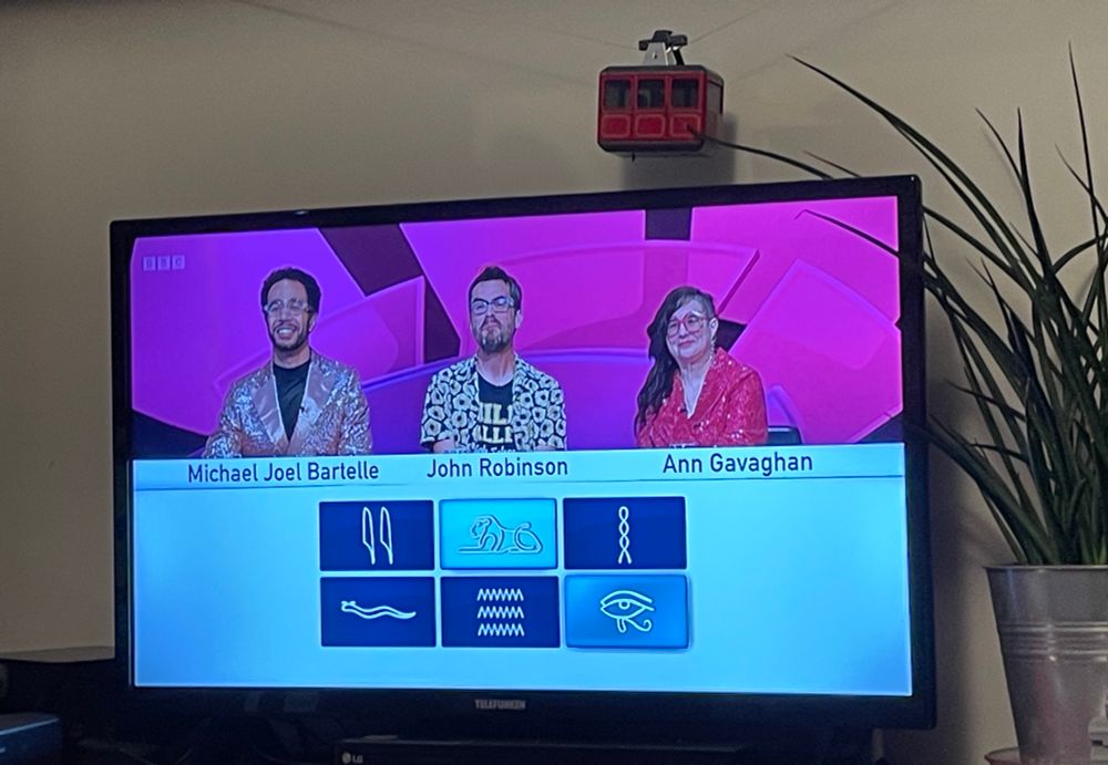 A TV with only connect on it. The team featured is Michael Joel Bartelle, John Robinson and Ann Gavaghan. Micheal and Ann are wearing sparkly jackets. 