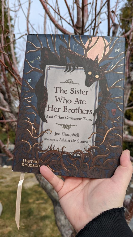 Showing off the cover of the short story collection, "The Sister Who Ate Her Brothers and Other Gruesome Tales," by Jen Campbell. The cover has a dark fox-like creature with empty white eyes around the title and trees and brambles around the border.