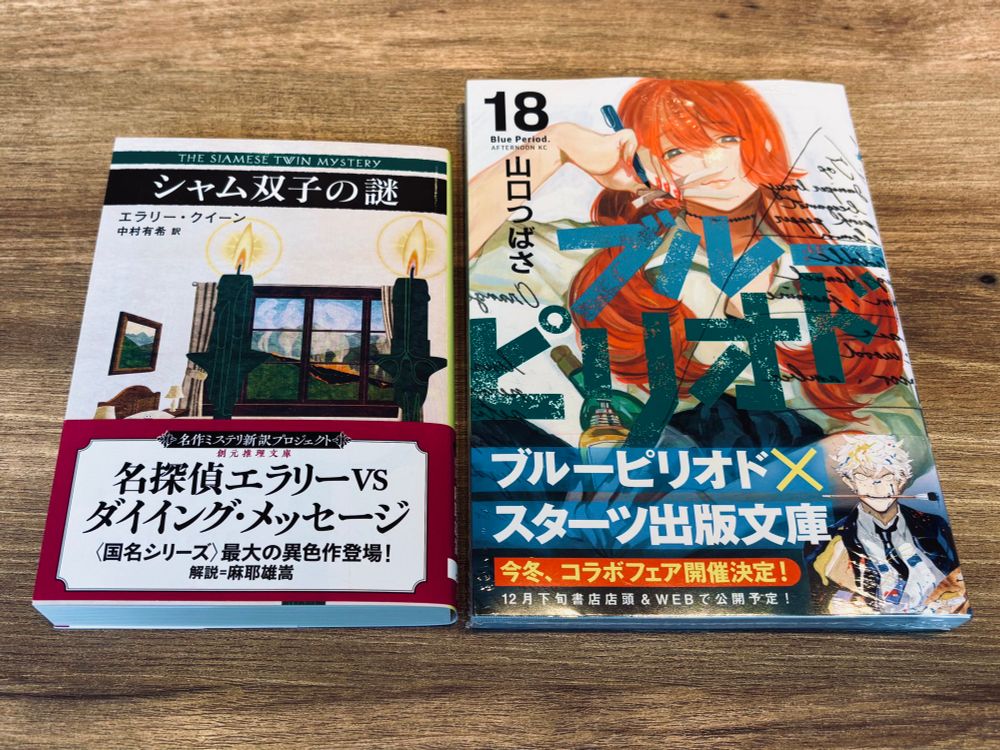 2冊の本。
◾️エラリー・クイーン著、中村有希訳『シャム双子の謎』（創元推理文庫）
◾️山口つばさ著『ブルーピリオド〈18〉』（アフタヌーン）