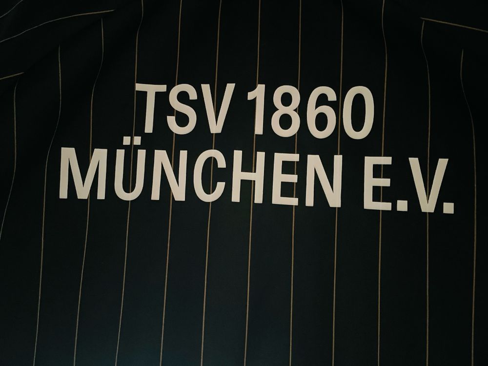 Alt-Text: Foto vom Trikot von 1860 München e.V., dem Nachbarverein und Erzfeind des heutigen Gegners Bayern München, dessen Fans aber eigentlich teilweise mit unseren befreundet sind.