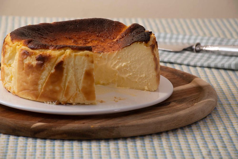 Una tarta de queso redonda en un plato. Una porción de la tarta está cortada.