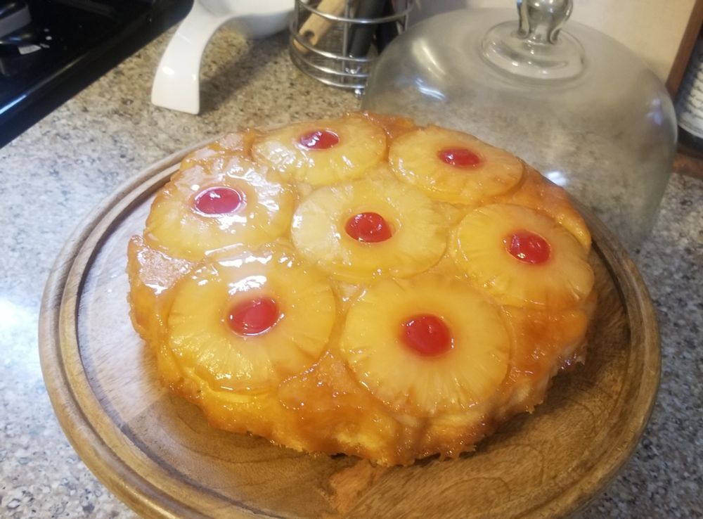 Pineapple upside down cake on a wooden cake stand.