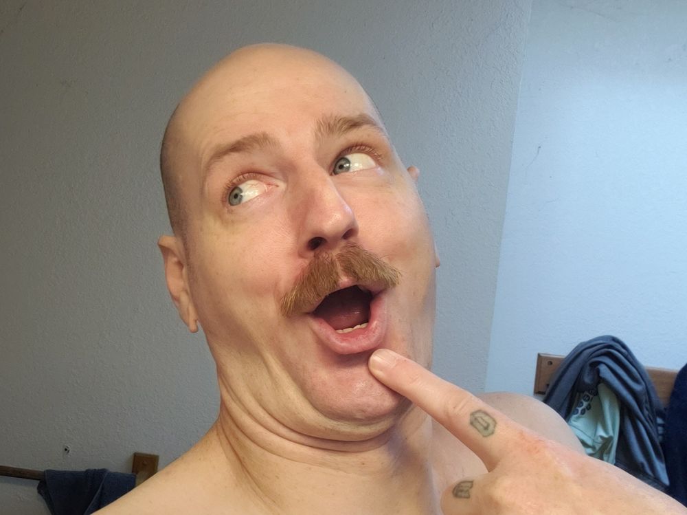 Some dork with a mustache doing and absolute goober face.