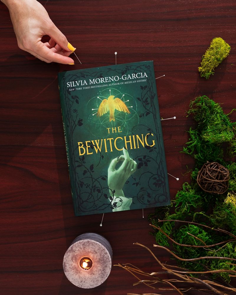 Book placed next to a candle and moss. 