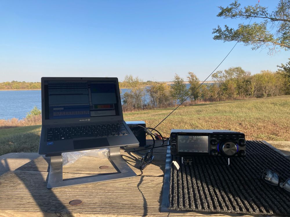 Amateur radio setup with a small laptop in the foreground, with John Redmond reservoir and dam in the background. 