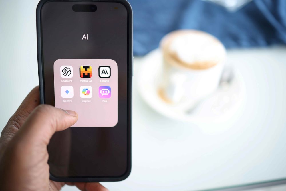 Person holding cell phone with Artificial Intelligence applications on them.