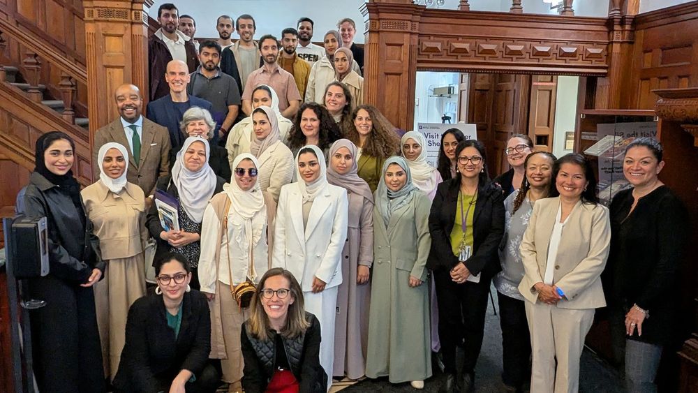 Visiting case managers from Abu Dhabi Family Care Authority and NYU Silver leadership pose on and in front of NYU Silver's lobby staircase.