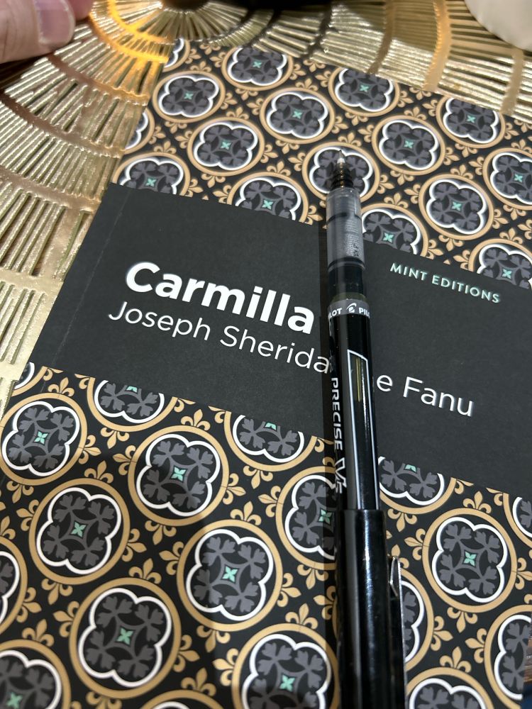 A copy of Carmella by Joseph Sheridan Le Fanu with a pen on top of it.