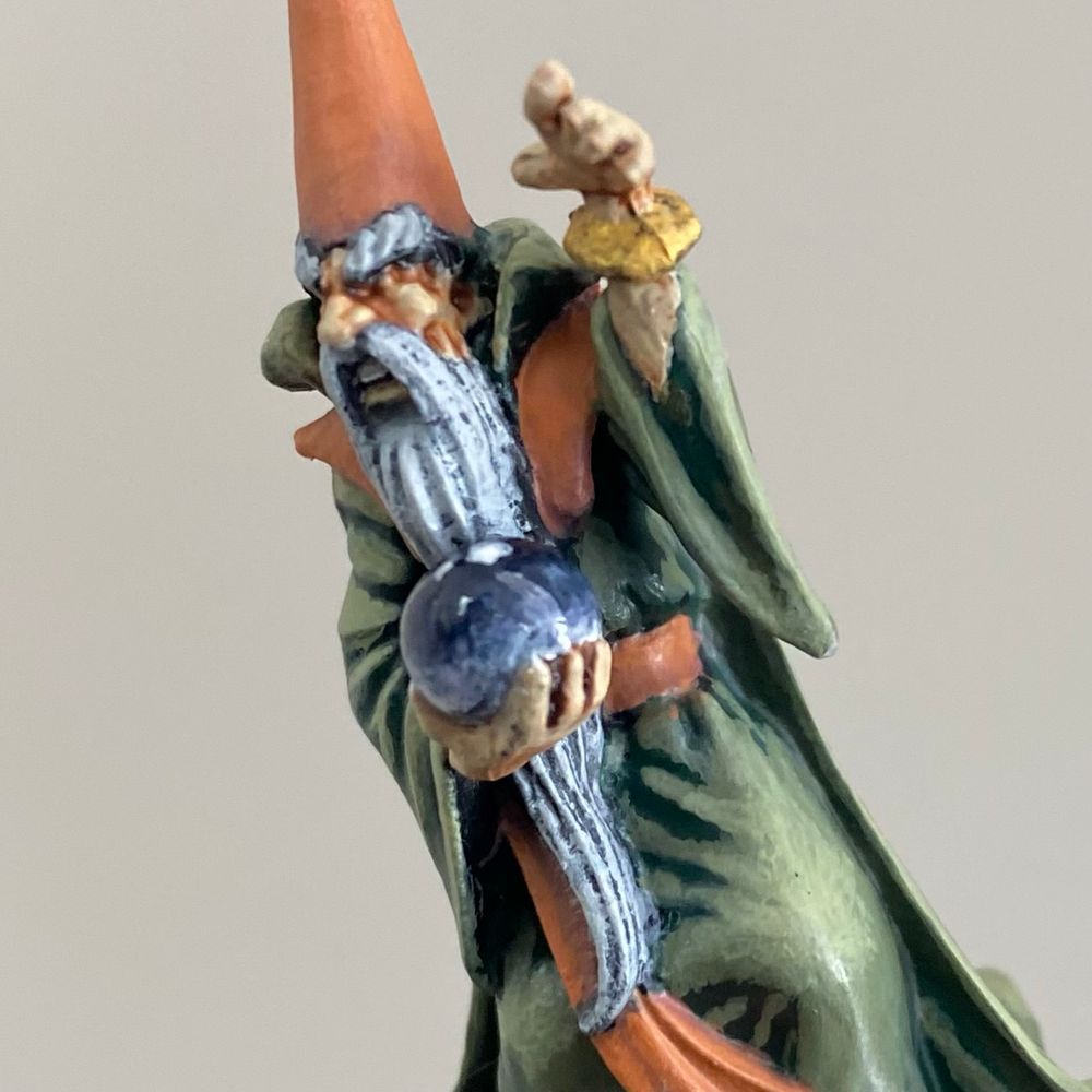 Closeup of a hand-painted miniature wizard with pointy hat and crystal ball. 