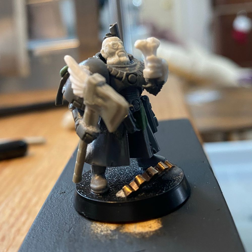A plastic miniature of a 40K inquisitor with a warhammer and power armor. 