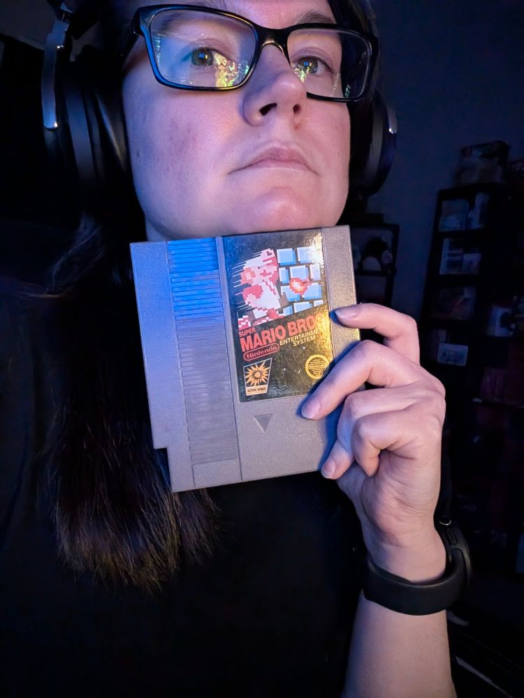 A person resting their chin on top of a square NES game cart of Super Mario Bros. 