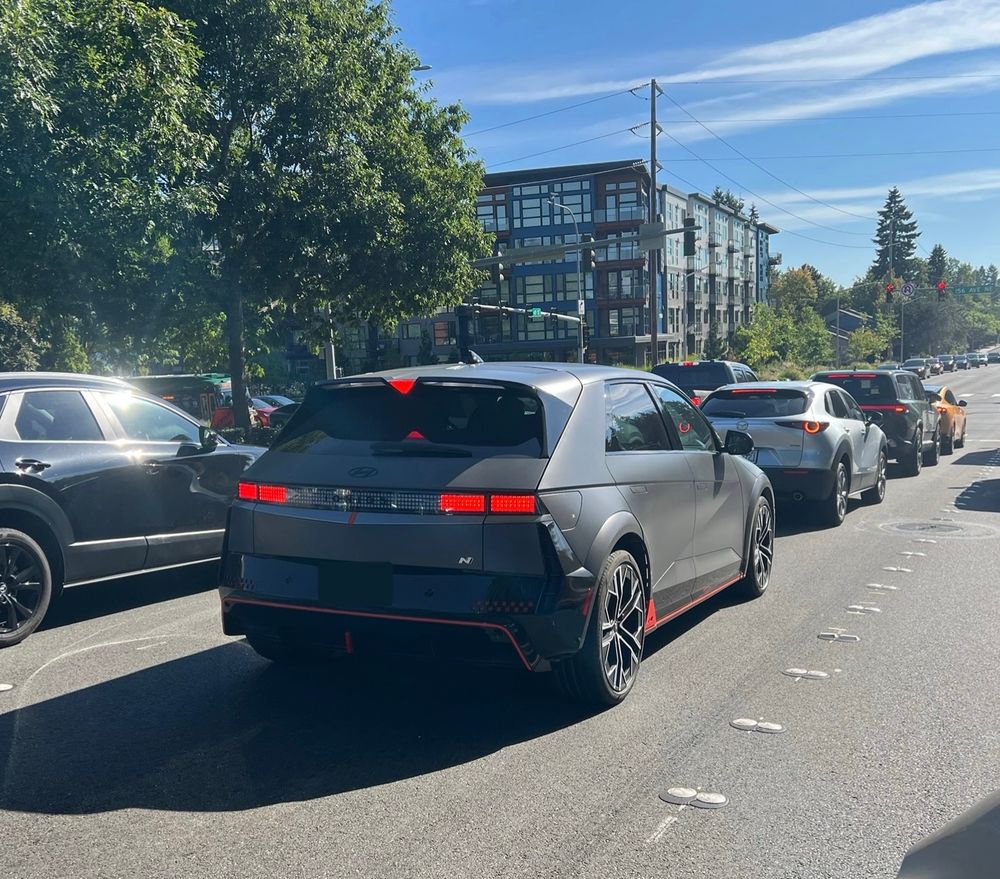 dark gray car from the back, in a sunlit road