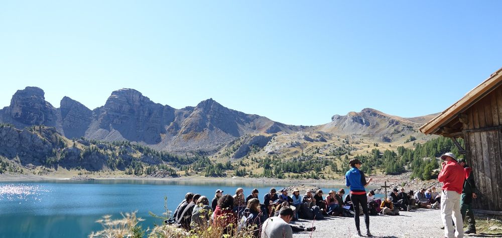 Alternet summer school students on field trip at Lac d'Allos, the lake and partly tree-covered mountains in the background.  
