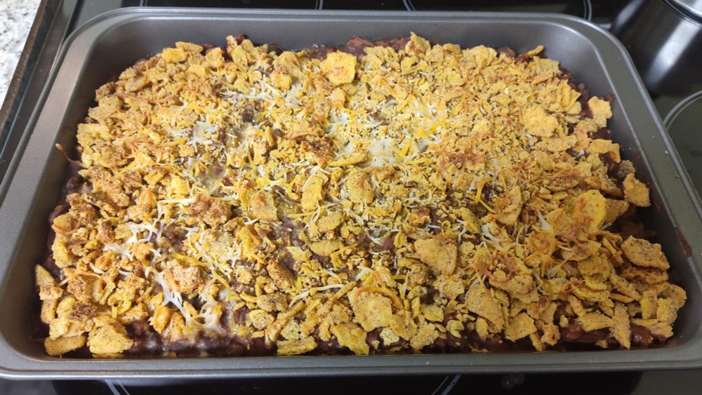 A pan of chili enchilada casserole with crunchy frito and cheese topping