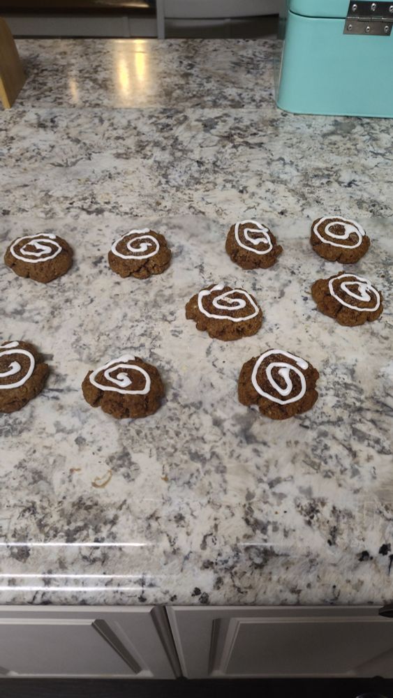 Brown cookies with white frosting in a nautilus spiral on wax paper 