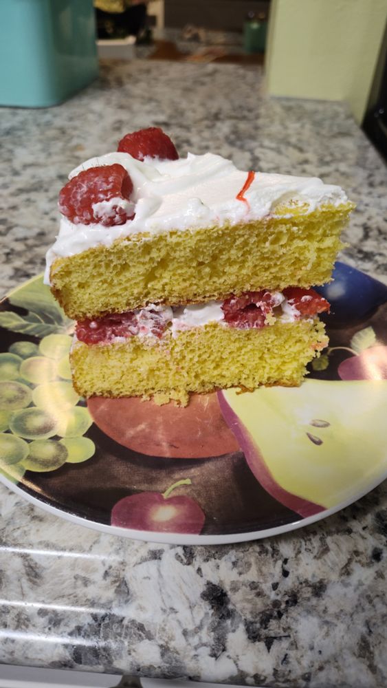 Slice of raspberry lemonade cake. Yellow lemon cake layered with whip cream and raspberries