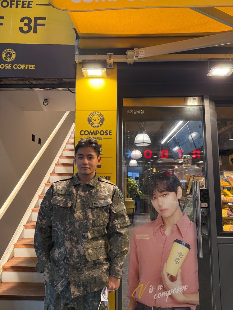 Taehyung of BTS standing next to a cutout of himself 