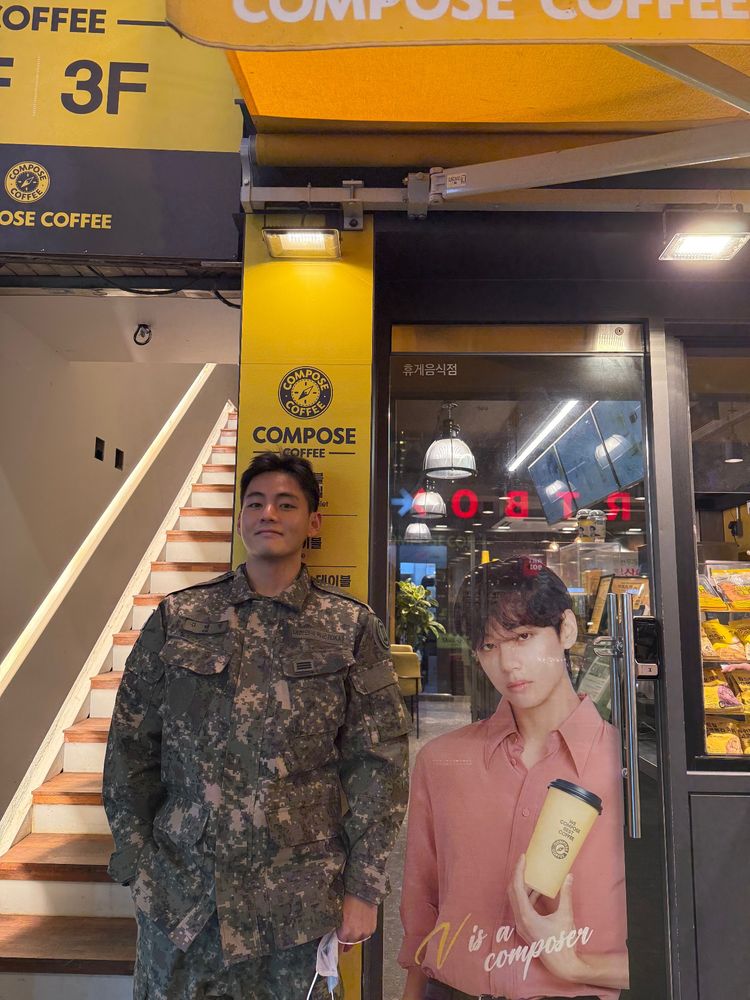 Taehyung of BTS standing next to a cutout of himself.