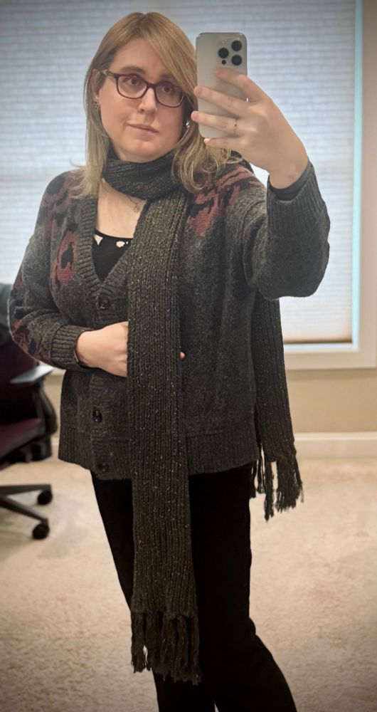 a woman poses in the mirror for a selfie. she is wearing a gray floral v-cut button up sweater over a black floral cami, a gray scarf with gold flecks, and black jeans; her hair is down and under her scarf a gold necklace is visible. her hair is let down over the scarf
