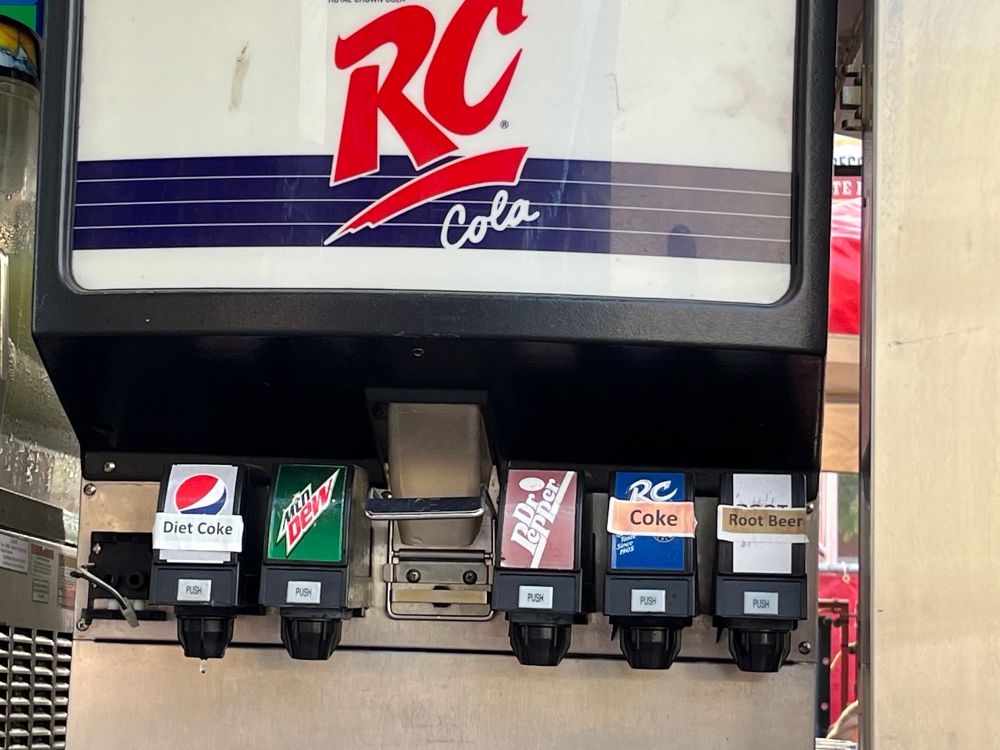 A fountain drink machine. The main branding says RC Cola. There’s a Pepsi-branded spout with a label that says Diet Coke, a RC-branded spout with a label that says Coke, and Dr Pepper and Mtn Dew that are normal. 