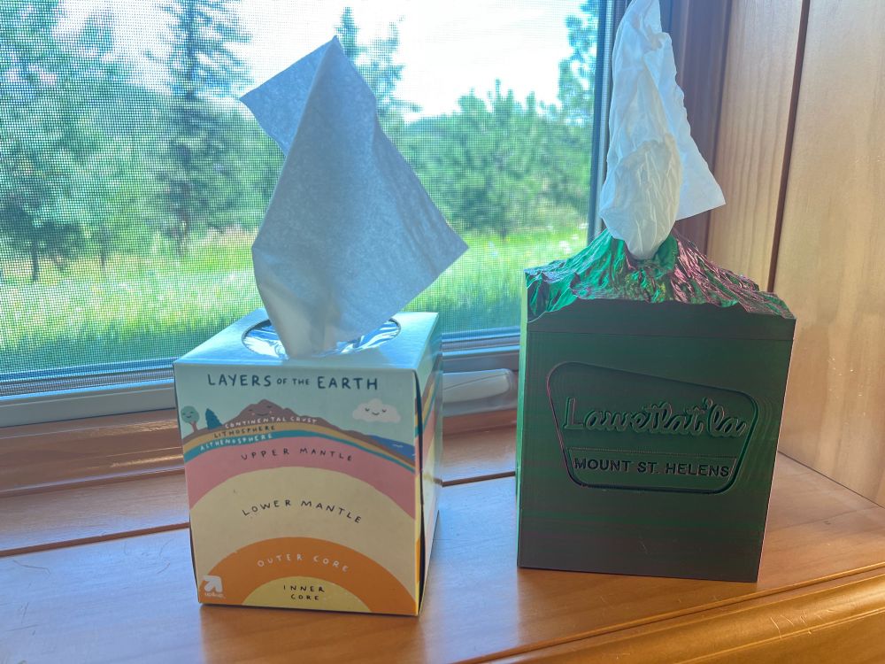 Left: a tissue box, with a multicolored diagram of Layers of the Earth on its side.

Right: a tissue box, 3D printed in the shape of Mount St Helens