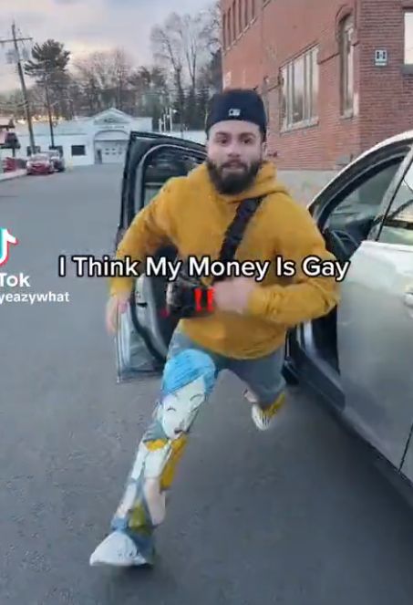 a man leaping out of a car, with text in front of him that reads "i think my money is gay"