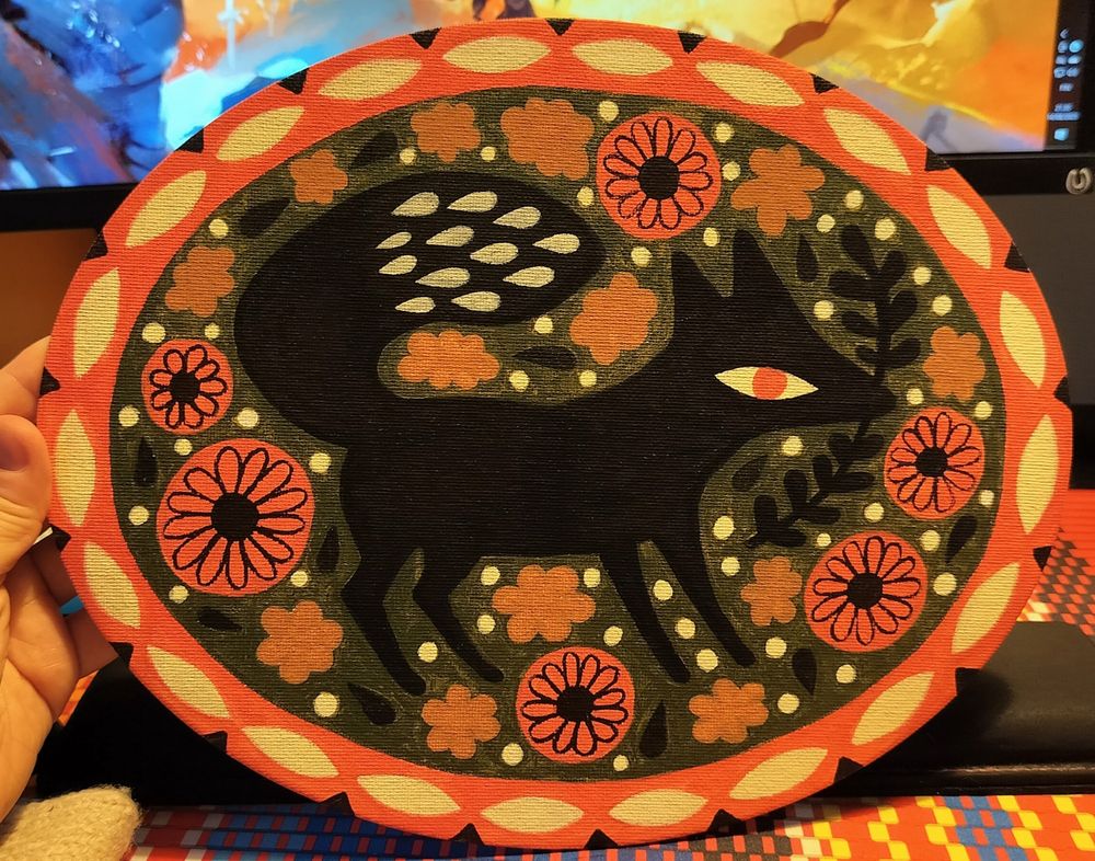 Oval shaped painting of a fox. The Black fox is in the middle, surrounded by red, cream, black and brown floral details. There is a black branch in its mouth. The Fox is just standing, looking at the right and it has red eyes. There are some droplet shaped white details in the tail. The background is olive green. There are red, cream and black frames painted around the animal.
