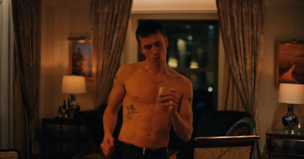 Film still from Babygirl in which Harris Dickinson dances shirtless while holding a glass of whiskey 