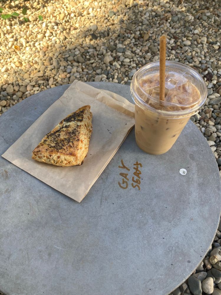 A coffee and scone on a table with graffiti that says “gay seats”