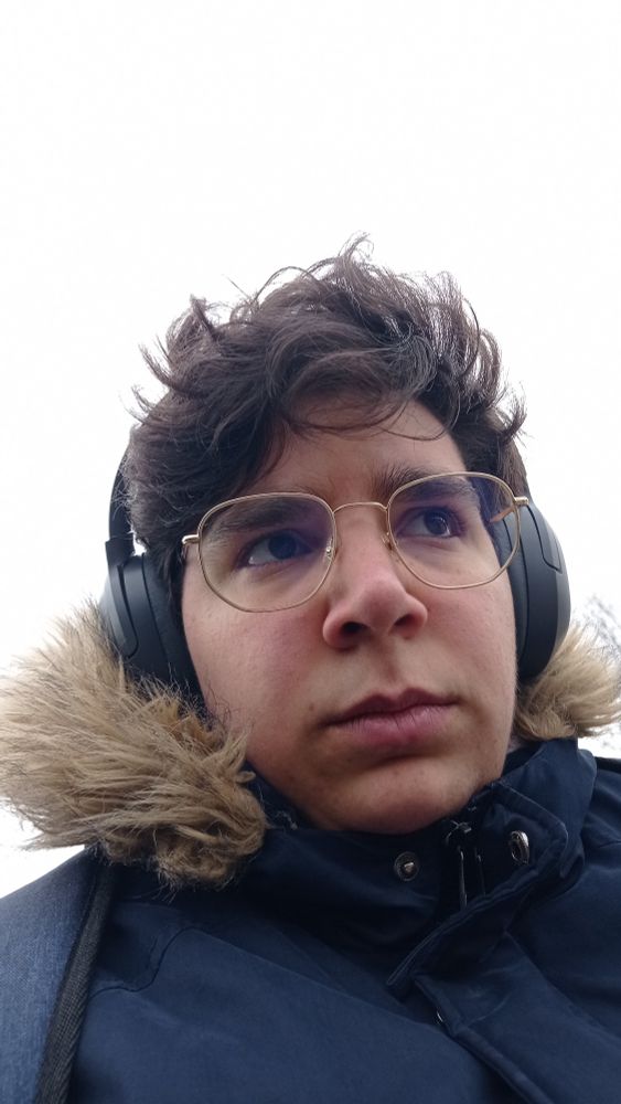 a close-up selfie of me with my coat and headphones on, wearing glasses.