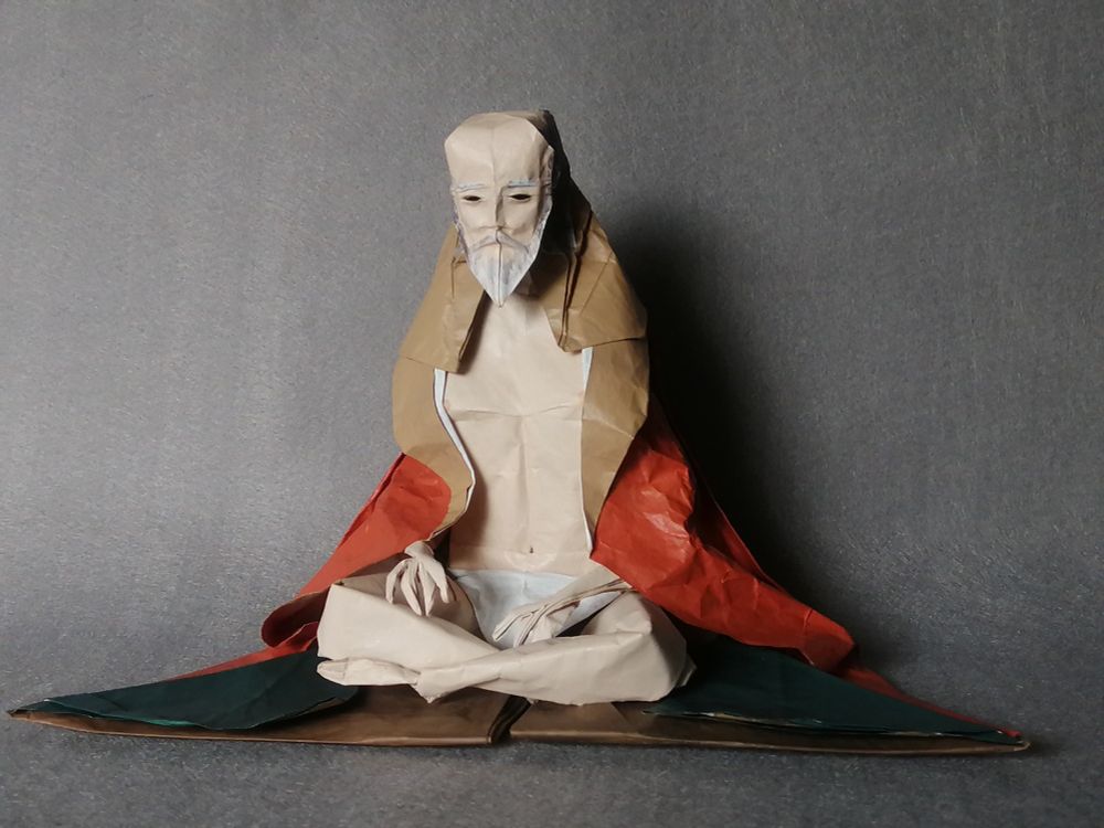 禿頭の老人が座っている折り紙像