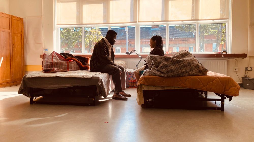 A father and his young daughter sit looking at each other on opposite beds in an asylum centre. They are Jide and Adamma, from the short film Kiki by Naomi Sheridan. 