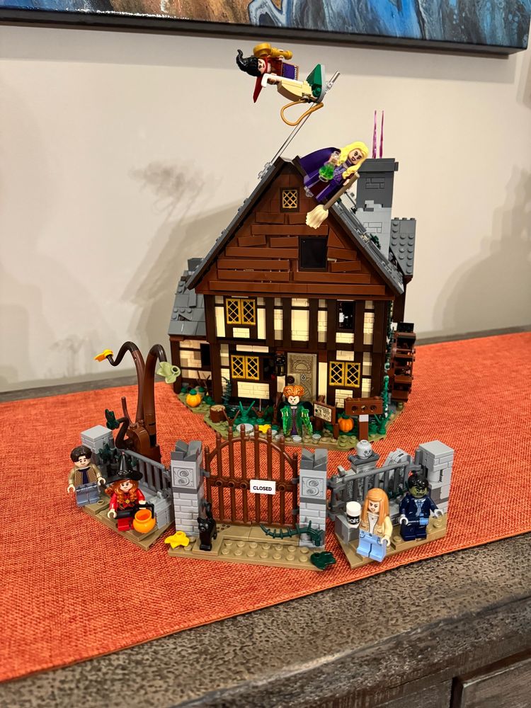 The Hocus Pocus LEGO set on a table with an orange runner. It has an additional minifigure that doesn’t come with the set but sort of looks like Billy Butcherson. 