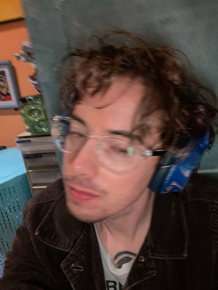 bespectacled white guy with short, gelled wavy hair