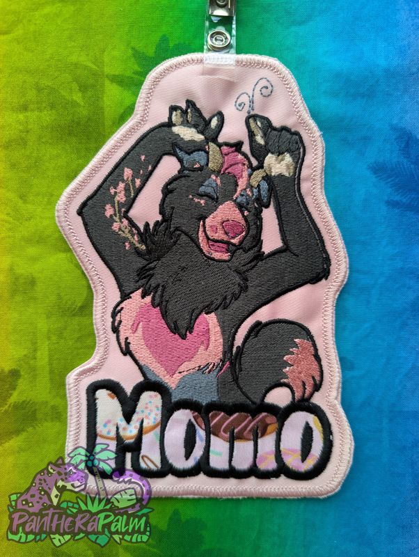 Machine embroidered artwork of happy black and pink goat/husky hybrid character